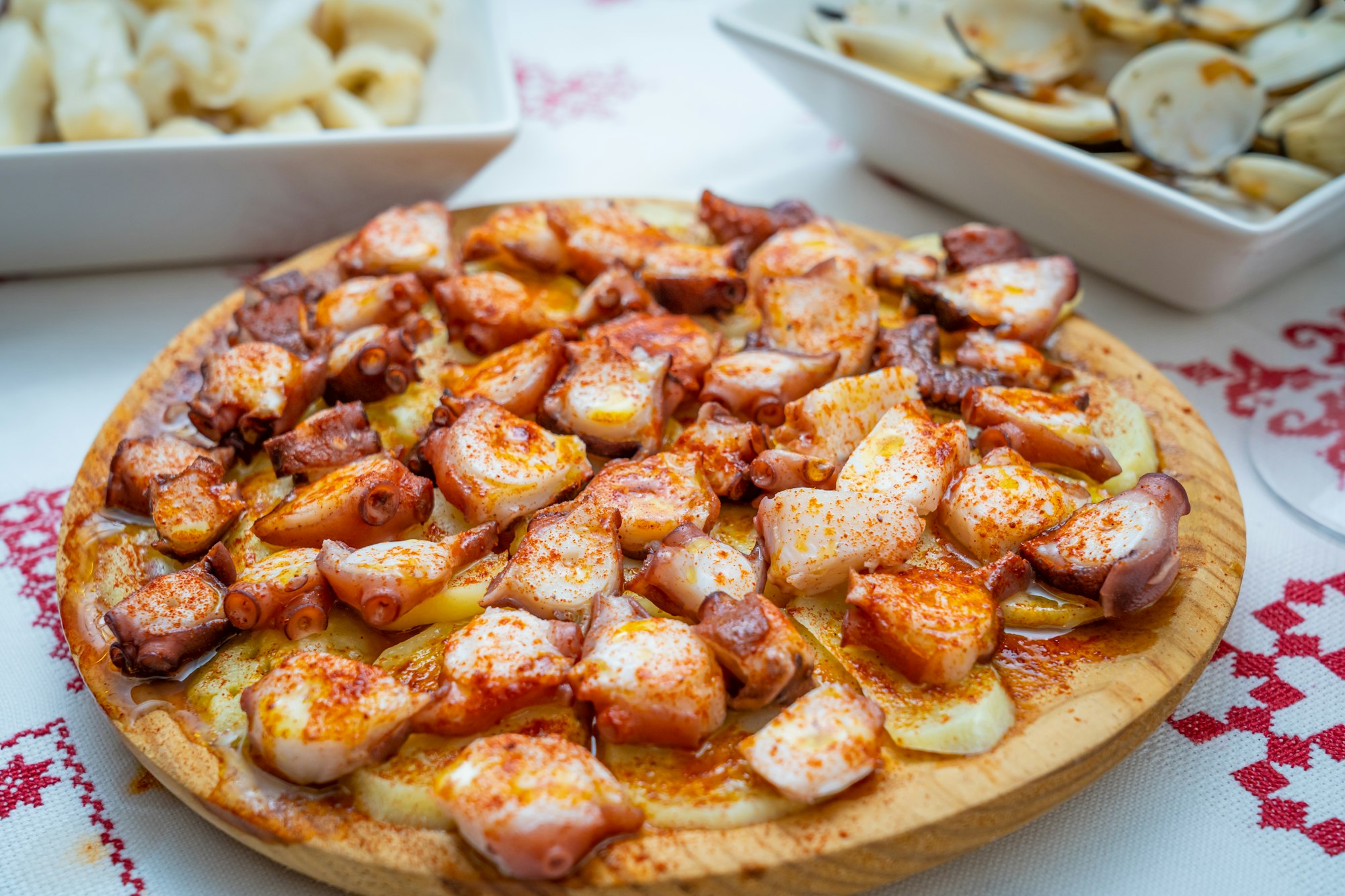 Closeup of cooked octopus pieces with spice and sauce on a wooden board on the table